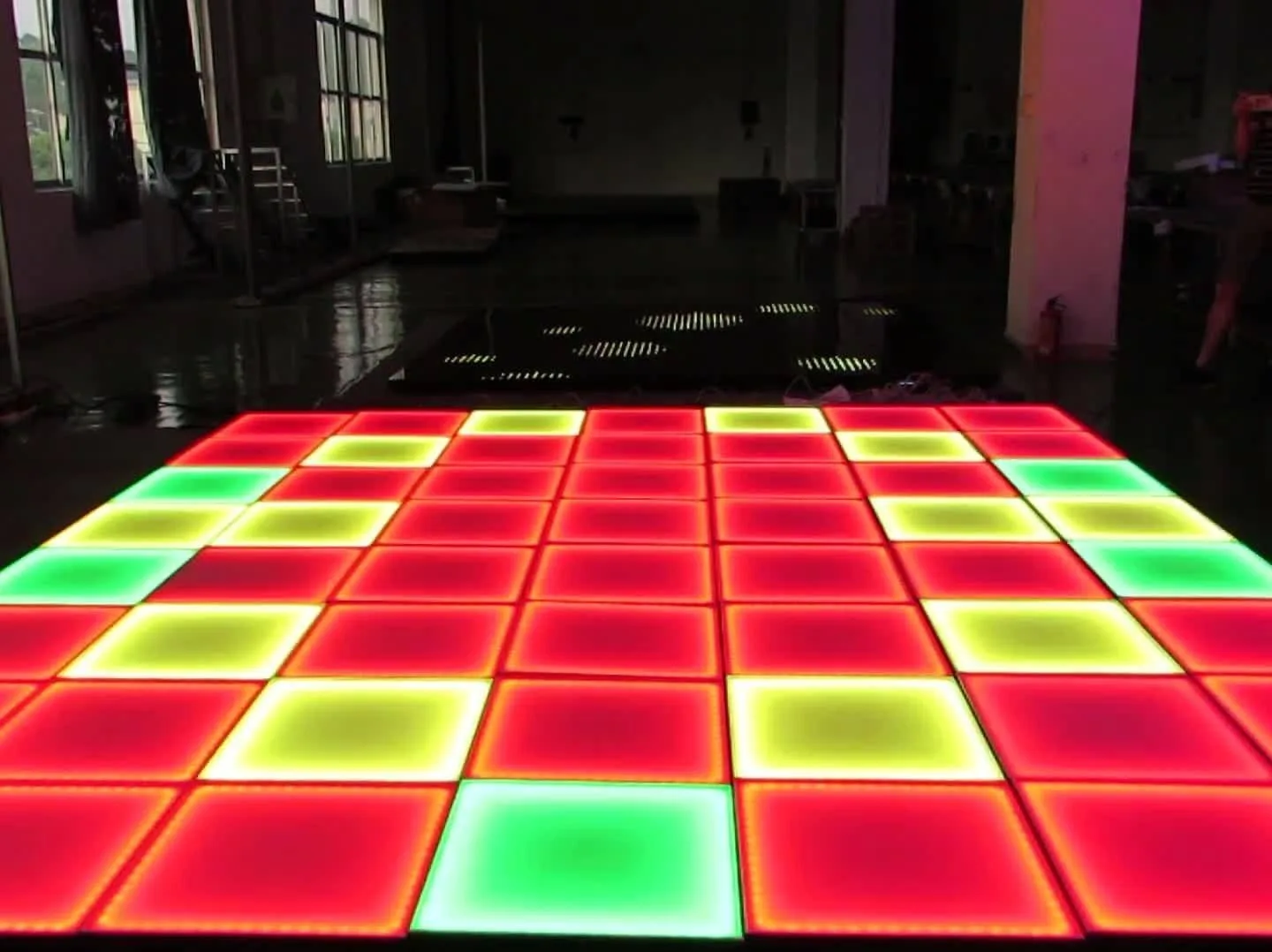 An indoor space with an LK - CH01 Rainbow dance floor presenting a pattern - generation lighting effect, with distinct colored squares forming a dynamic pattern.