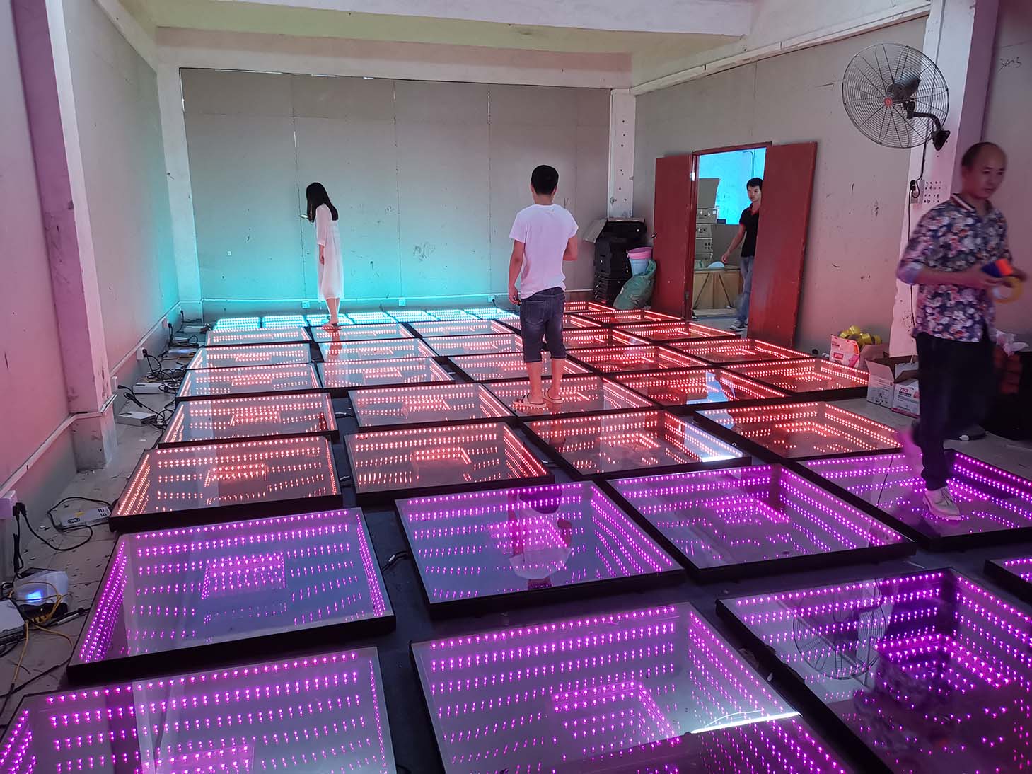 An indoor space with an LK - CH01 Rainbow dance floor presenting a pattern - generation lighting effect, with distinct colored squares forming a dynamic pattern.