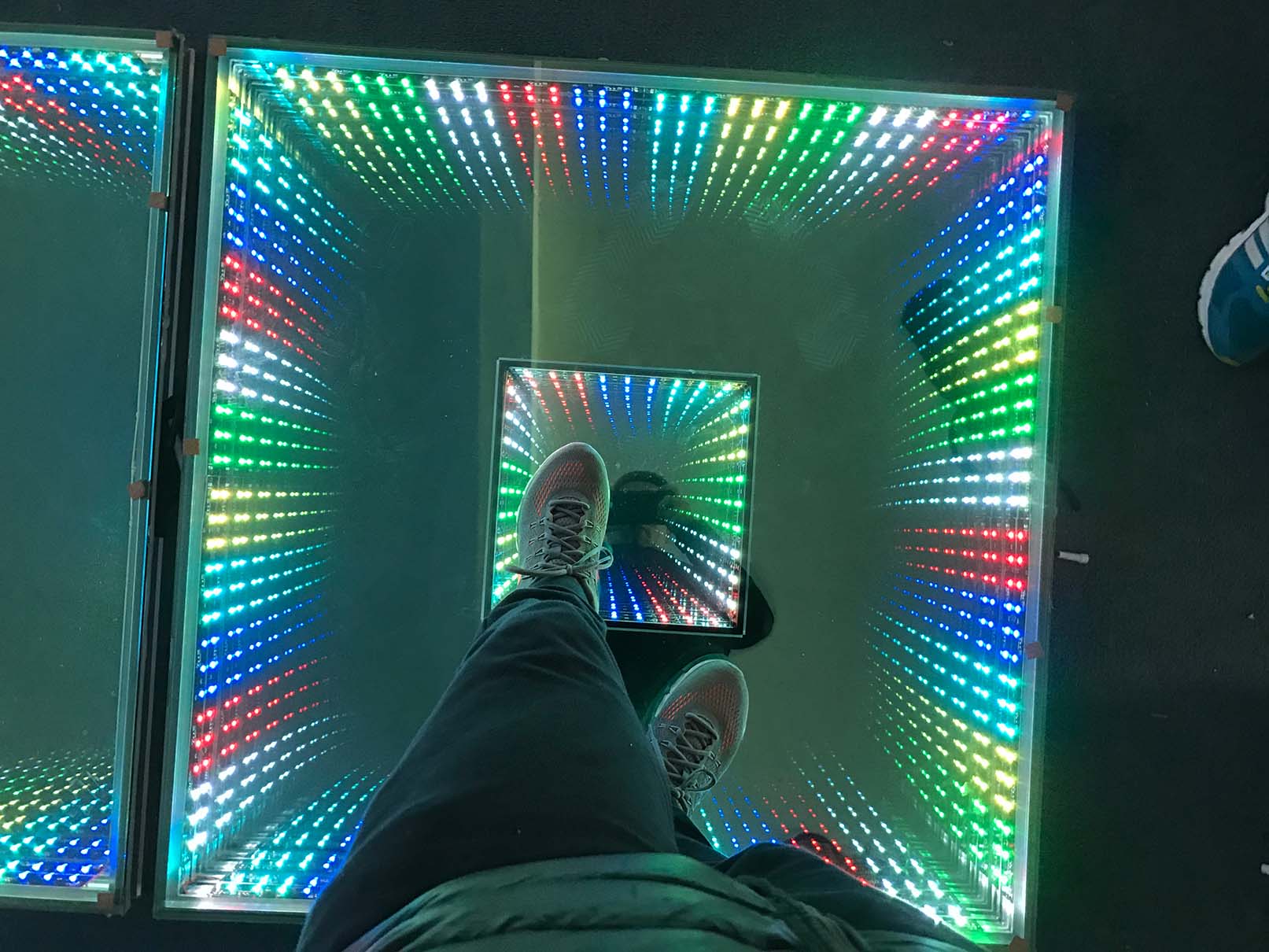 An outdoor setting with an LK - CH01 Rainbow dance floor displaying a mixed RGB lighting effect, featuring a spectrum of colors and an eye - catching design in the background.
