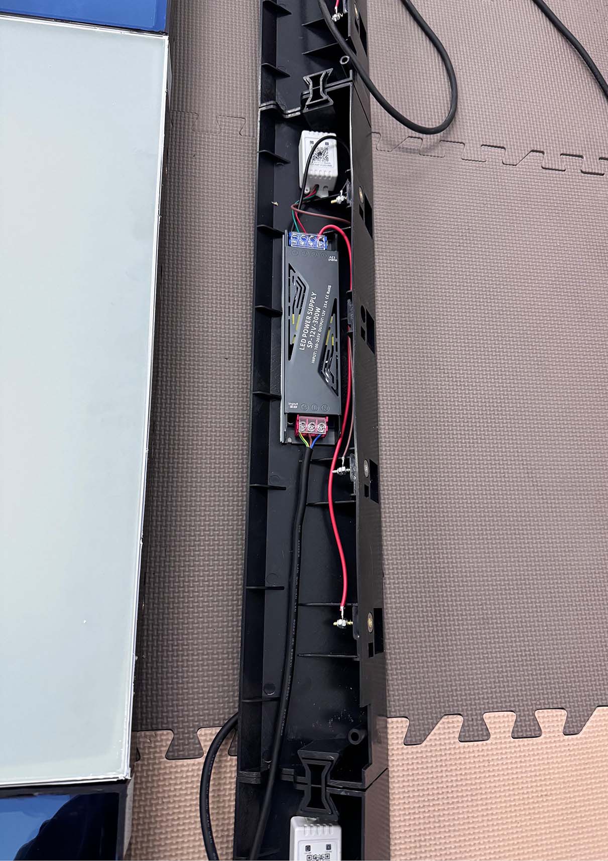 Professional installation of customized LED dance floor panels using wall drilling for vertical mounting.