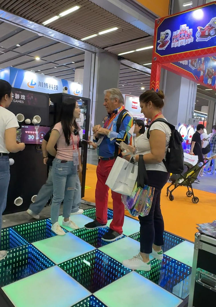Clients interacting with a 3D LED dance floor at an international lighting show in Guangzhou.