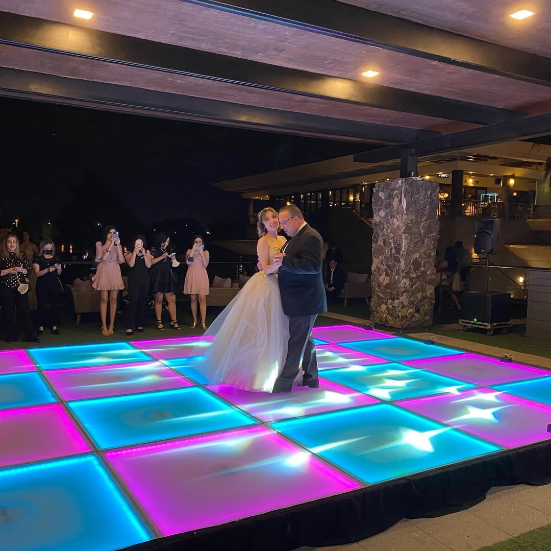 Outdoor wedding dance floor featuring a colorful LED dance floor with vibrant blue and pink lighting effects for a romantic first dance.