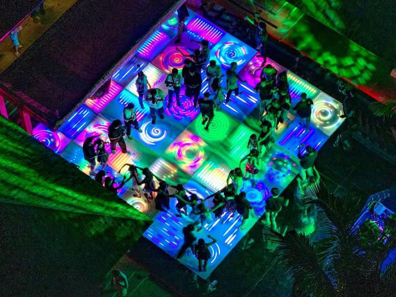 Vue aérienne d’une piste de danse LED colorée personnalisée avec motifs lumineux vibrants lors d’un gala en extérieur.