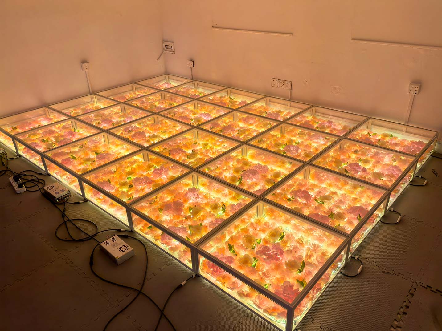 Piste de danse LED florale testée avec cadre en acier inoxydable et éclairage interne orange chaud dans une salle.