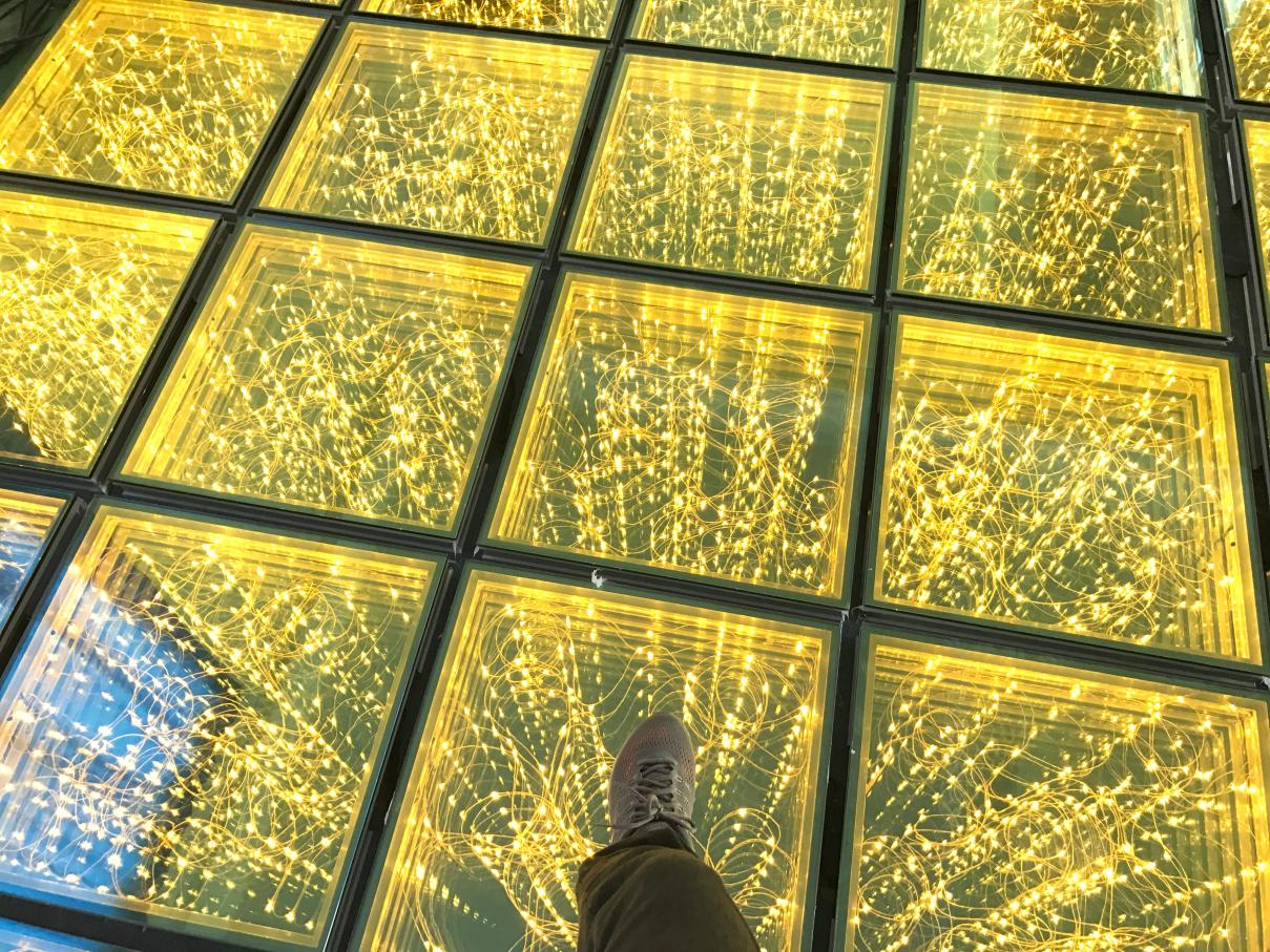 Gros plan d’une personne marchant sur panneaux or monochromes de piste de danse étoilée 3D avec profondes réflexions infinity.