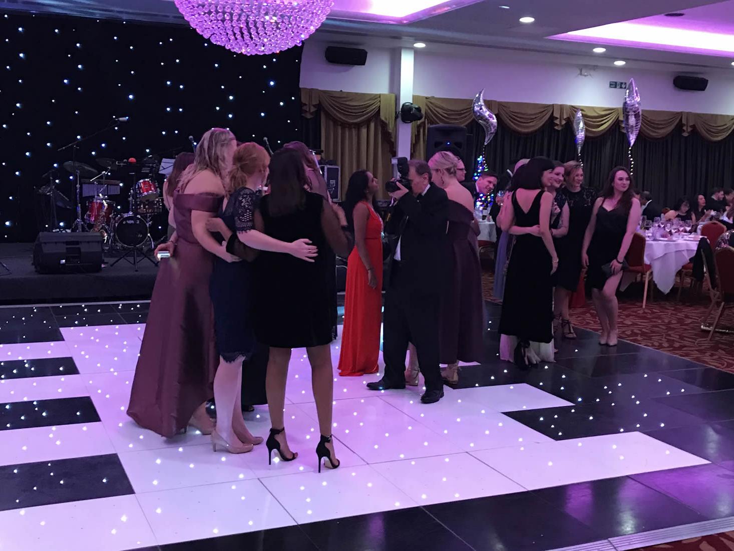Guests gathering on a checkered black and white LED starlit dance floor at a corporate gala event.