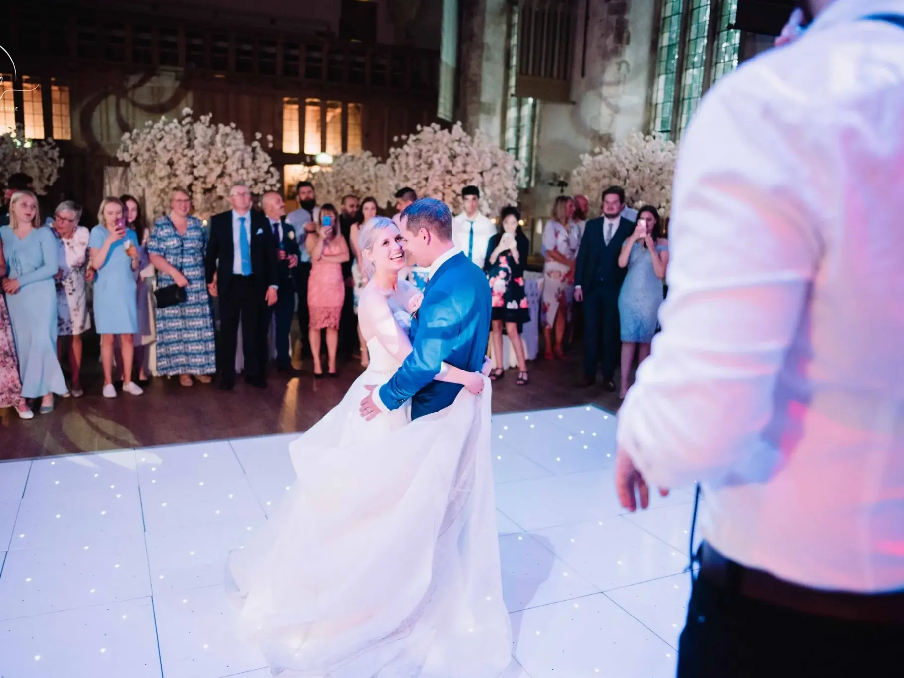 Piste de danse étoilée blanche avec mariés s’embrassant lors d’une réception intérieure.
