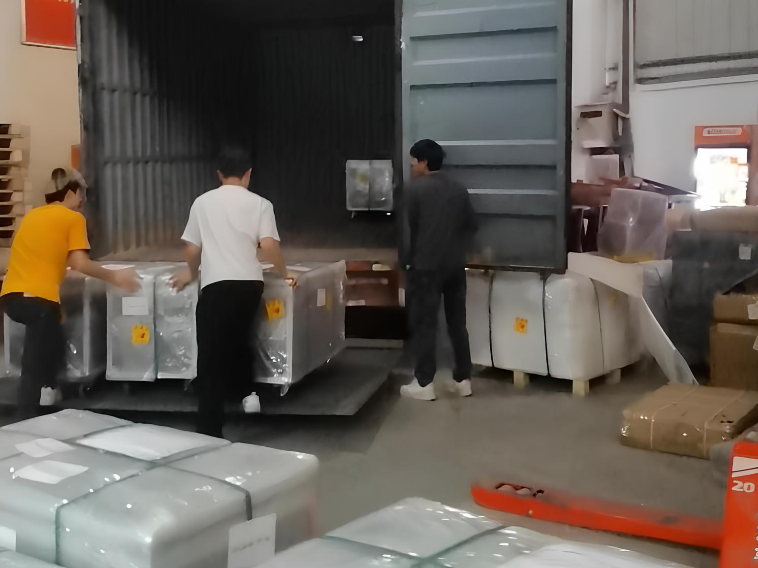 Factory workers loading pallets of LED dance floor panels into a shipping container for export.