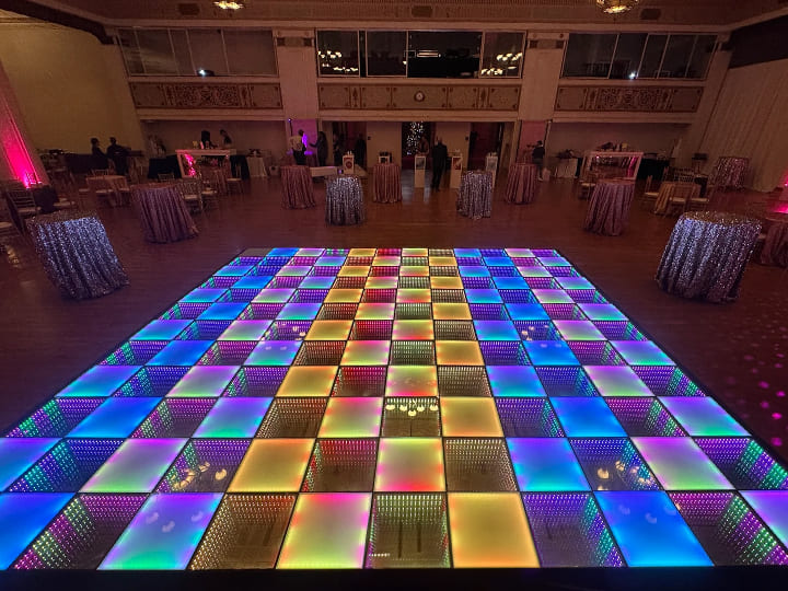 A 20x20ft 3D mirror LED dance floor glowing with colorful lights in a wedding banquet hall.