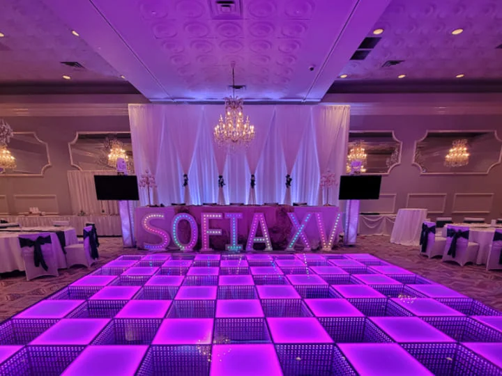 A glowing purple 3D LED dance floor layout set up in a decorated ballroom for an event.