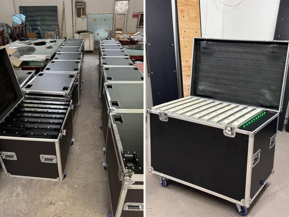 Open flight cases packed with LED dance floor panels inside a factory workshop.