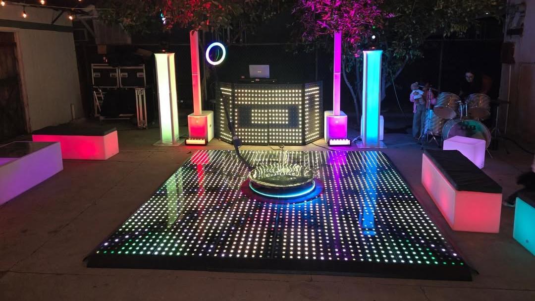 Montaje para una fiesta al aire libre con una plataforma 360 situada en el centro de una pista de baile LED Pixel y equipo de DJ.
