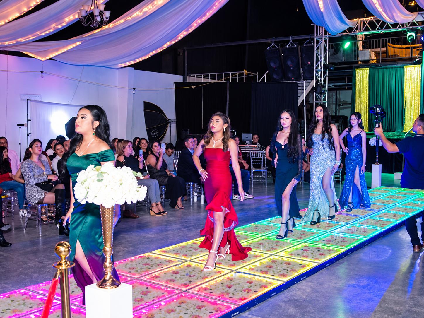 Modelos desfilando sobre una pista de baile LED floral iluminada, configurada como pasarela para un desfile de moda.