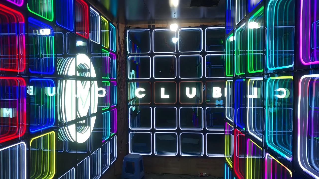 Immersive room installation featuring custom LED infinity mirror wall panels with illuminated CLUB lettering and glowing 3D tunnel effects.