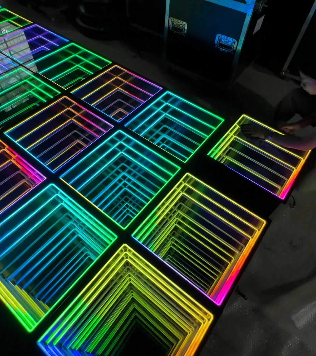 Close-up of vibrant multicolored LED infinity mirror wall panels and infinity mirror dance floor modules during assembly and testing.