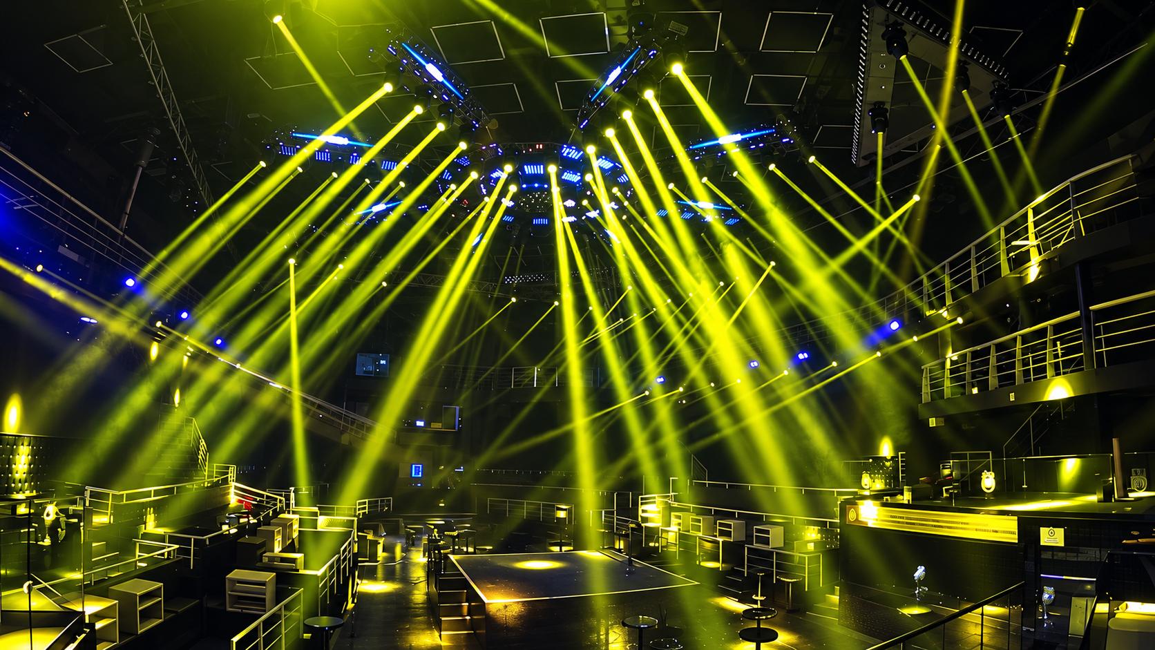nightclub-stage-lighting-setup-beam-effects Traditional nightclub stage lighting setup with powerful yellow moving head beam lights cutting through the venue ceiling.